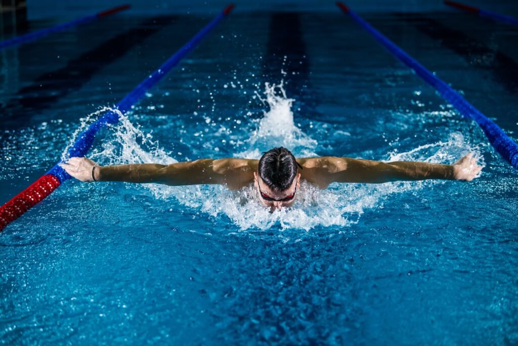 A man swimming laps in a pool, wearing a Garmin Forerunner.