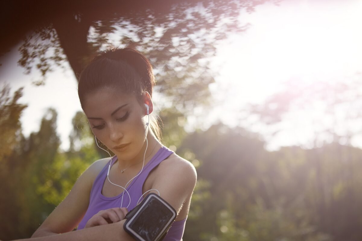 A woman with headphones in, ready to go for a run. She's made running a habit.