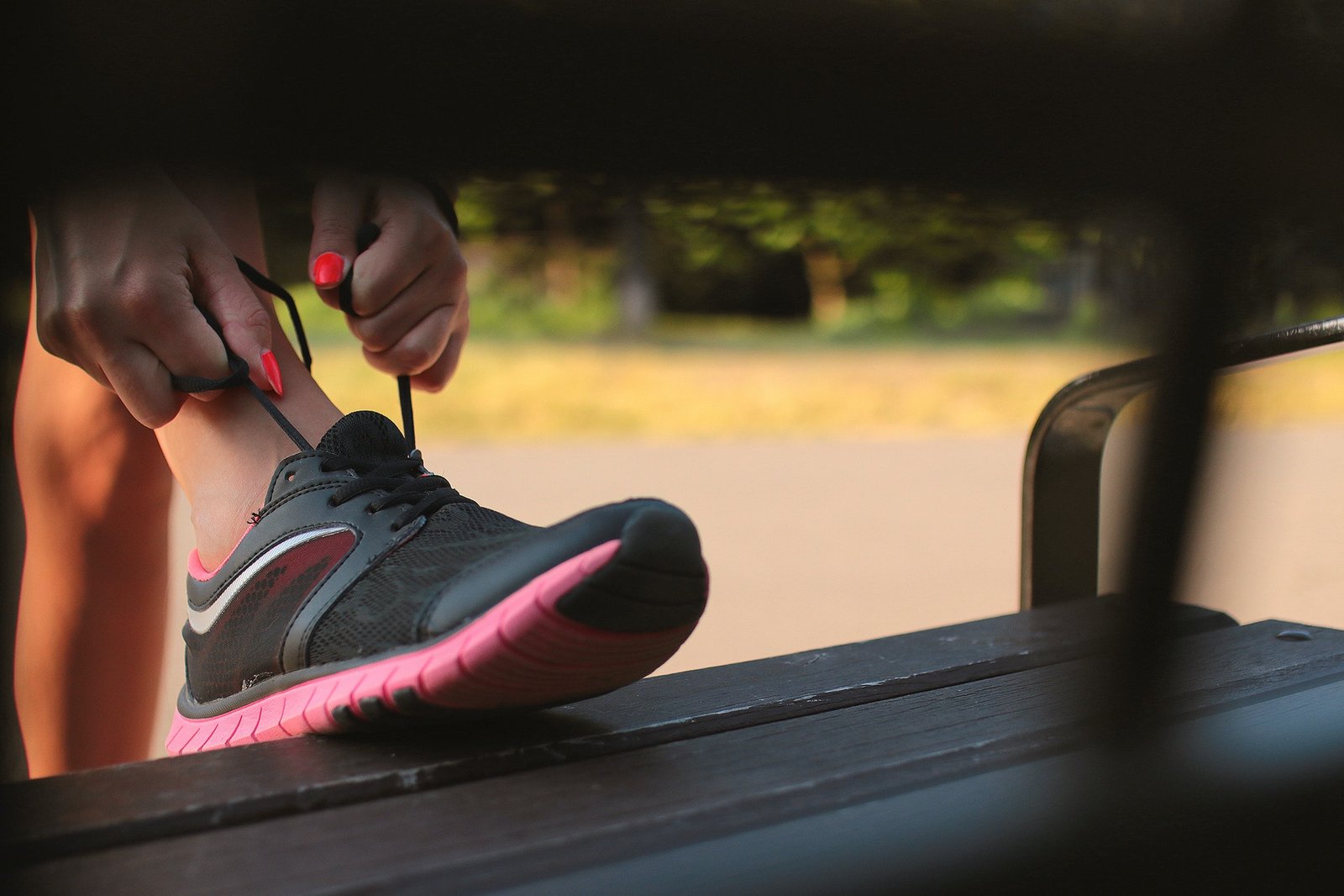 A woman tying her shoes on a park bench. This is the first step in how to get back into running.