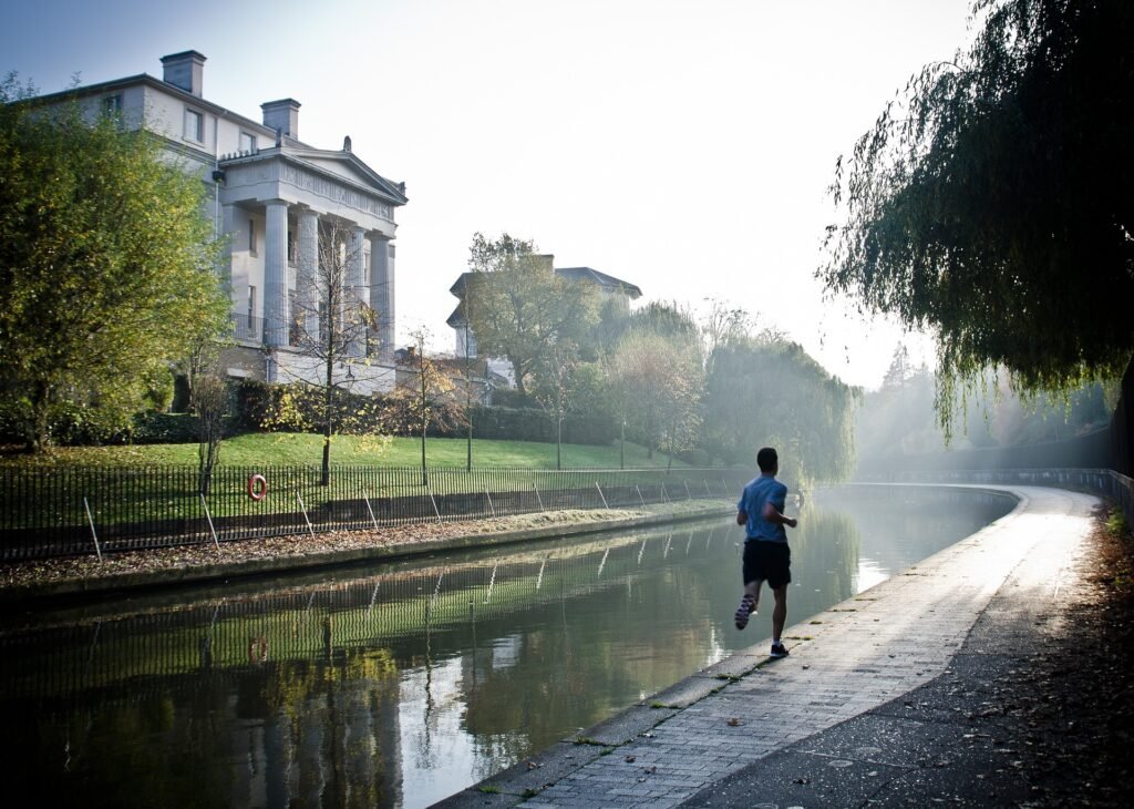 A man running along a river while training using a Pfitz marathon plan.