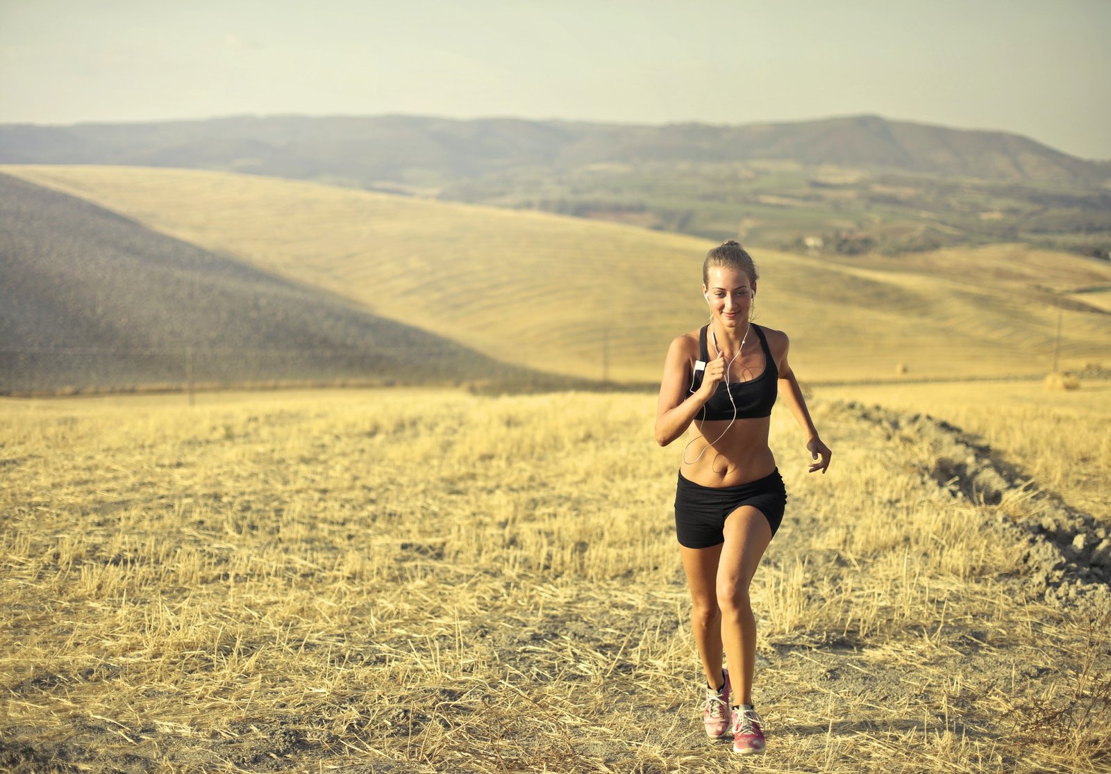 A woman running through an open field and enjoying the benefits of trail running.