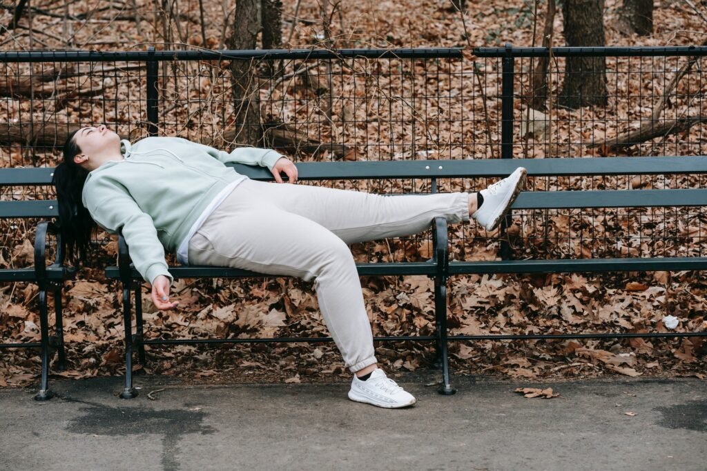 A woman laying on a bench, recovering after running a marathon