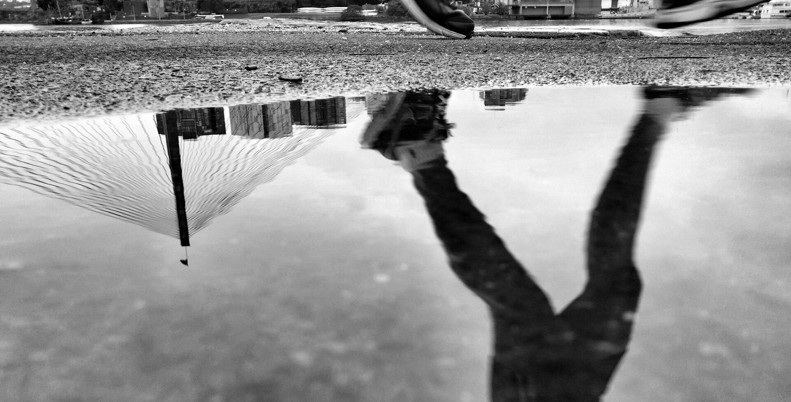 A man running with his image reflected in a puddle while training for a marathon.