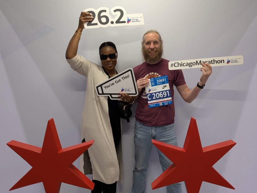 My wife and I holding signs that said ChicagoMarathon and 26.2, taken at the Chicago Marathon Expo.